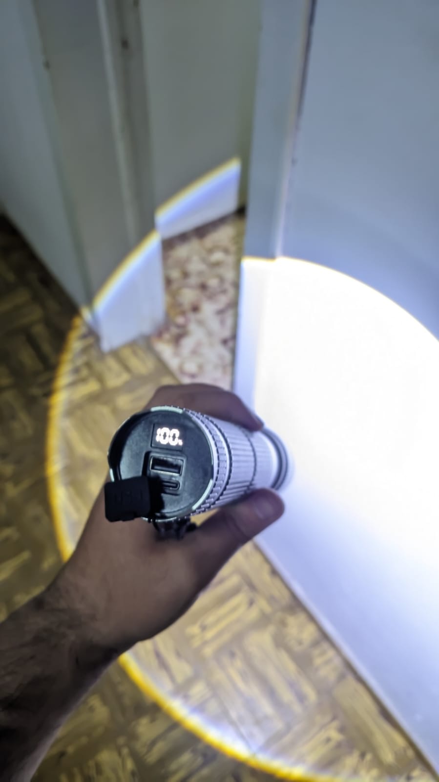Persona sosteniendo la linterna con el haz frontal encendido y el indicador digital visible