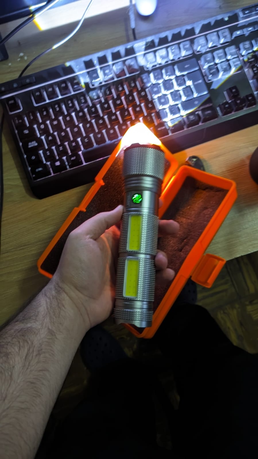 Linterna sostenida sobre su estuche rígido naranja abierto